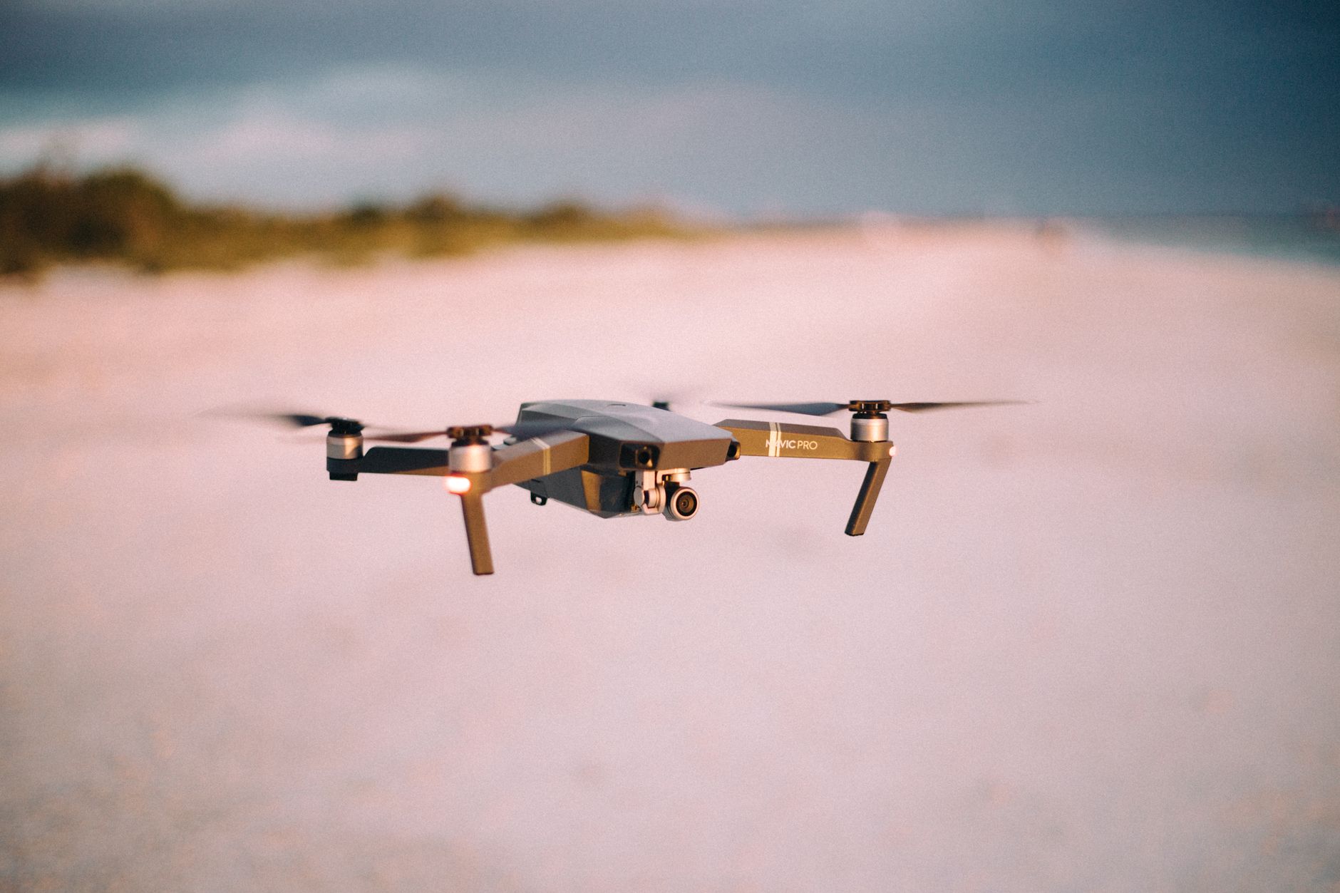 A sleek drone in flight over a beach during sunset, capturing stunning aerial views.